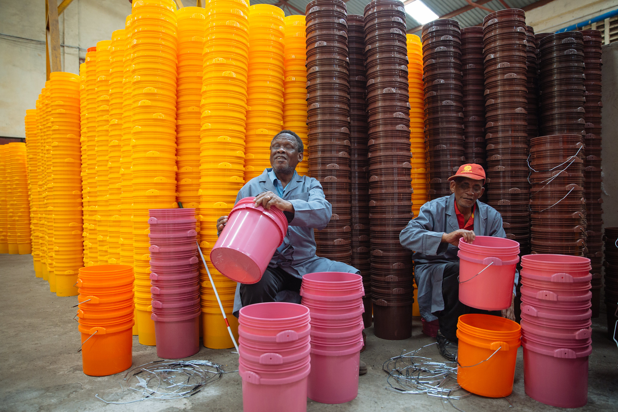 Disabled Factory Workers Stack Colorful Buckets in a Warehouse
